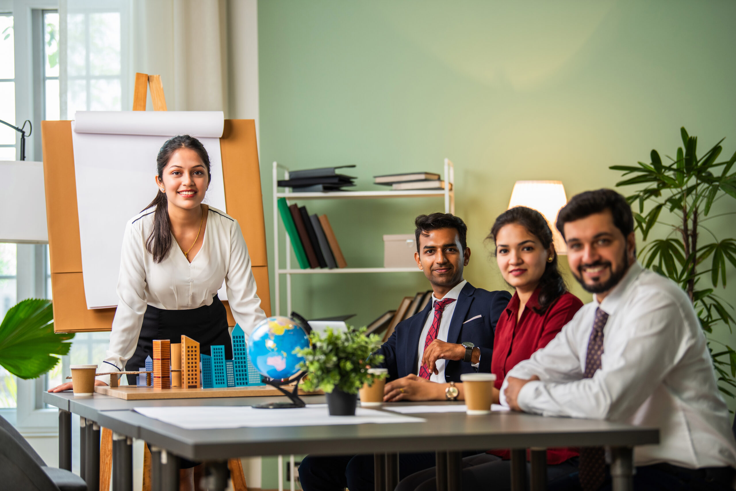Confident Indian asian female boss or trainer make whiteboard presentation at team office meeting in a coworking space